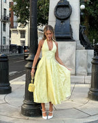 Robe midi jaune en tissu léger, dos nu, avec jupe plissée parfaite pour les soirées d'été.