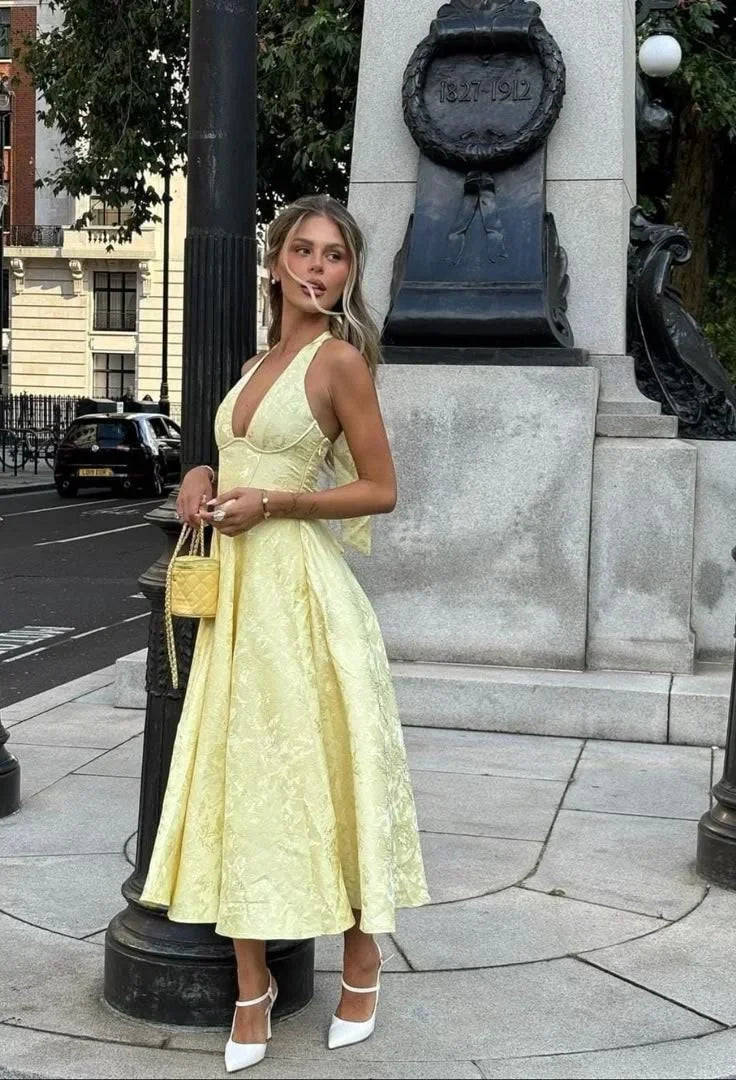 Robe midi jaune, dos nu, avec jupe plissée en tissu léger, parfaite pour les soirées d'été.