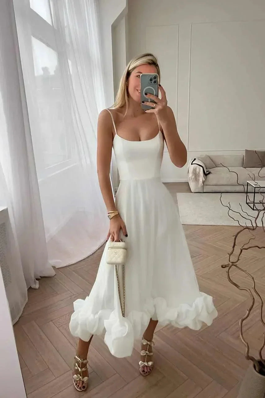 Robe midi blanche à bretelles fines, en coton léger, avec volants et design fluide, idéale pour les journées d'été.