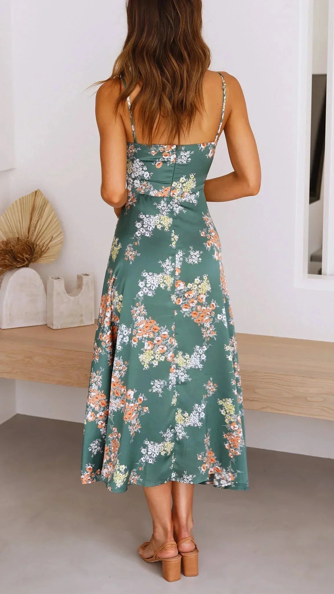 Robe midi en satin vert avec motifs floraux, nœud avant et bretelles fines, idéale pour un look estival décontracté.