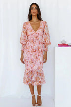 Robe midi fleurie à manches longues, col en V, en tissu fluide, avec volants pour une silhouette élégante au printemps.
