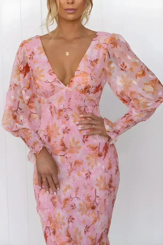 Robe midi fleurie en tissu fluide, manches longues, col en V, et volants pour un look printanier élégant.