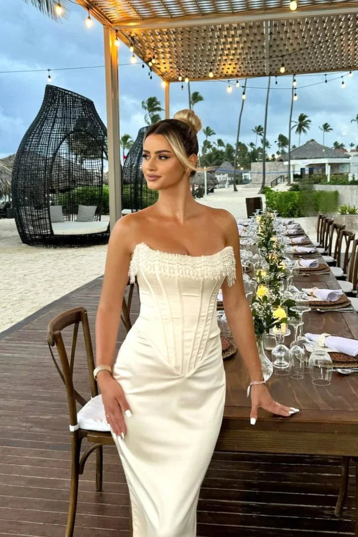 Robe midi ivoire avec bustier perlée, corset ajusté et design élégant pour soirées et cocktails.