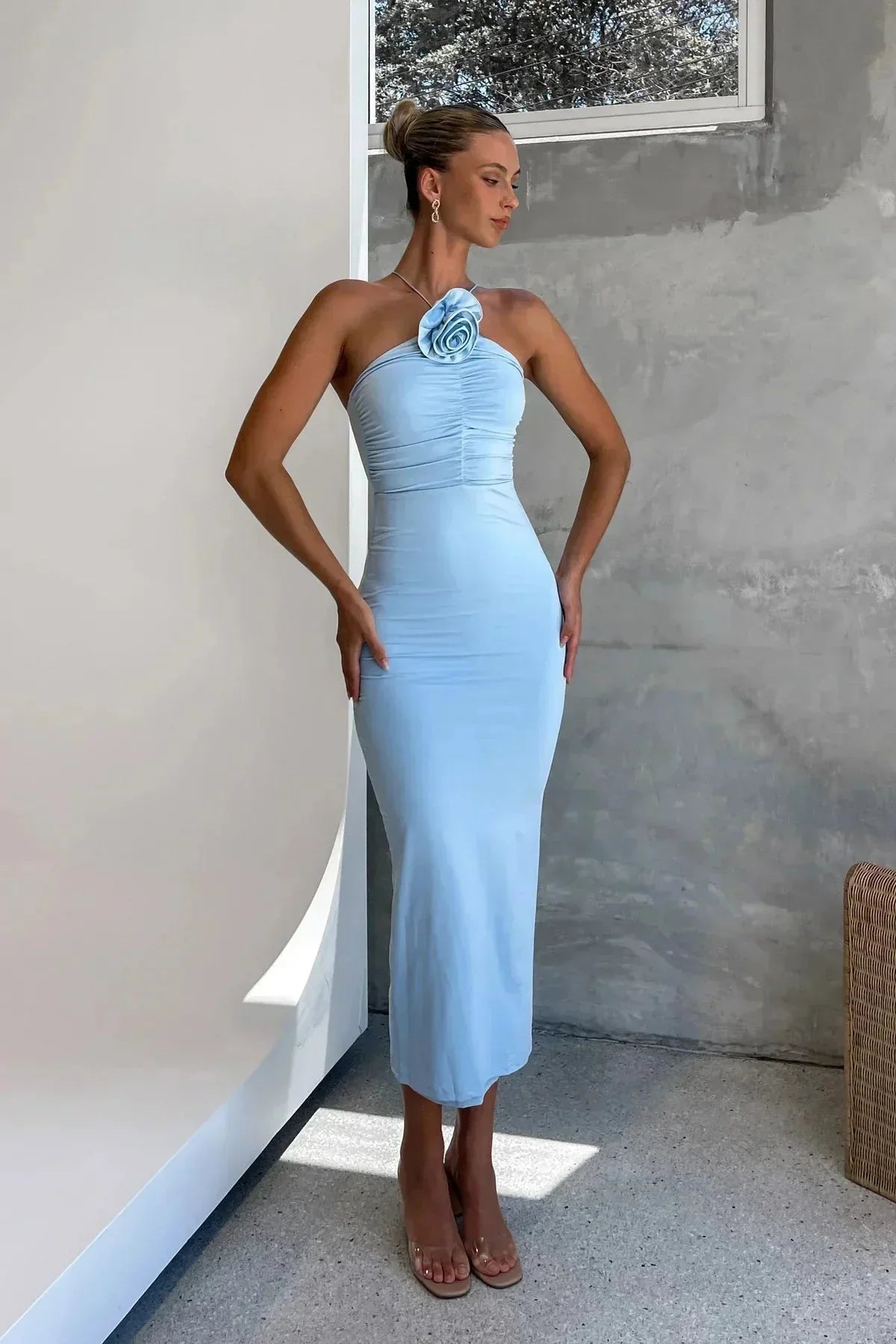 Robe midi moulante avec un col asymétrique et des détails floraux, fabriquée en tissu stretch pour un ajustement confortable.