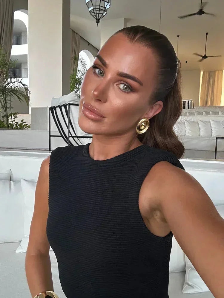 Robe midi noire sans manches en tissu léger, ornée de franges, idéale pour les soirées élégantes.