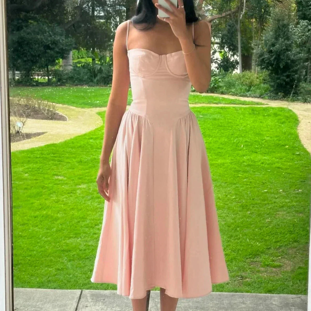 Robe midi rose en coton, avec bustier ajusté et jupe évasée, idéale pour les journées d'été.