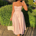 Robe midi rose avec bustier ajusté et jupe évasée en tissu léger, idéale pour les journées d'été.