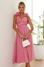 Robe midi rose en tissu léger, bustier torsadé et volants, idéale pour un look féminin et confortable.