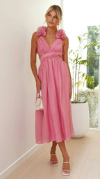 Robe midi rose en tissu léger, bustier torsadé, avec volants délicats sur le bas pour un look féminin.