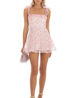 Robe courte A-ligne en coton léger avec détails en dentelle et nœuds aux épaules, parfaite pour des soirées d'été.