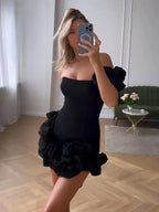 Robe courte asymétrique en tissu fluide, épaules dénudées avec volants, parfaite pour les soirées élégantes.