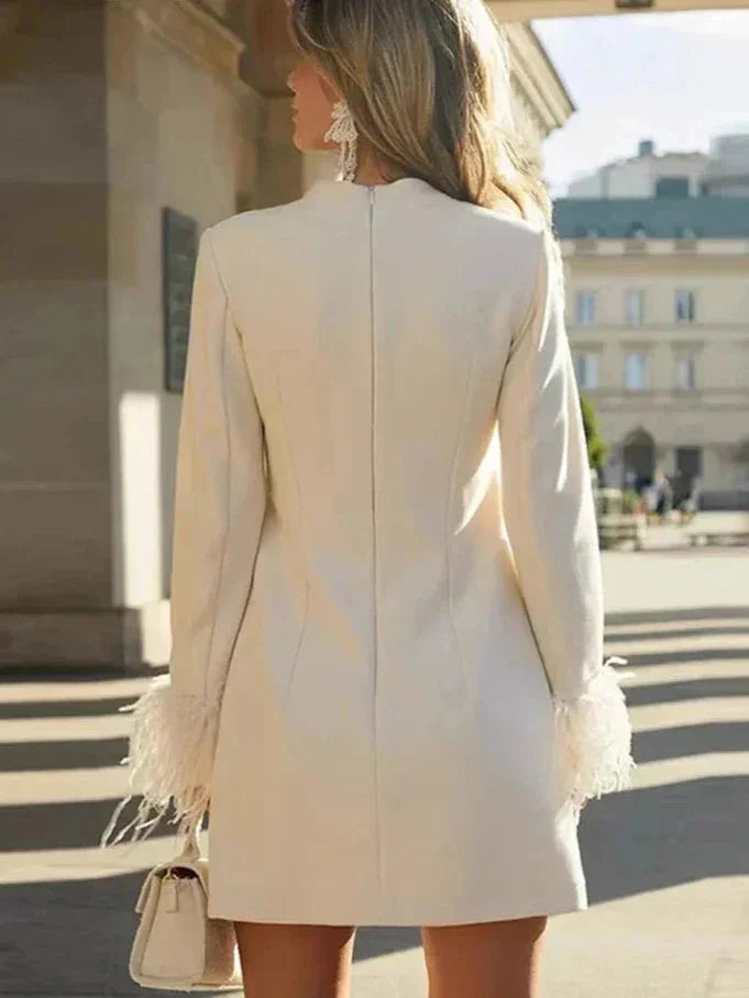 Robe courte blanche à manches longues en tissu léger, ornée de plumes, offrant une coupe droite élégante pour soirées.