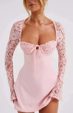 Robe courte blanche en dentelle avec manches longues et dos nu, coupe ajustée, idéale pour une soirée cocktail élégante.