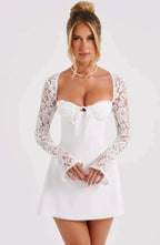 Robe courte blanche en dentelle, manches longues et dos nu, finition ajustée, parfaite pour une soirée cocktail élégante.