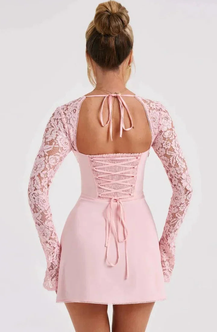 Robe courte blanche en dentelle, manches longues, dos nu, coupe ajustée pour soirées cocktail. Détails délicats en dentelle.