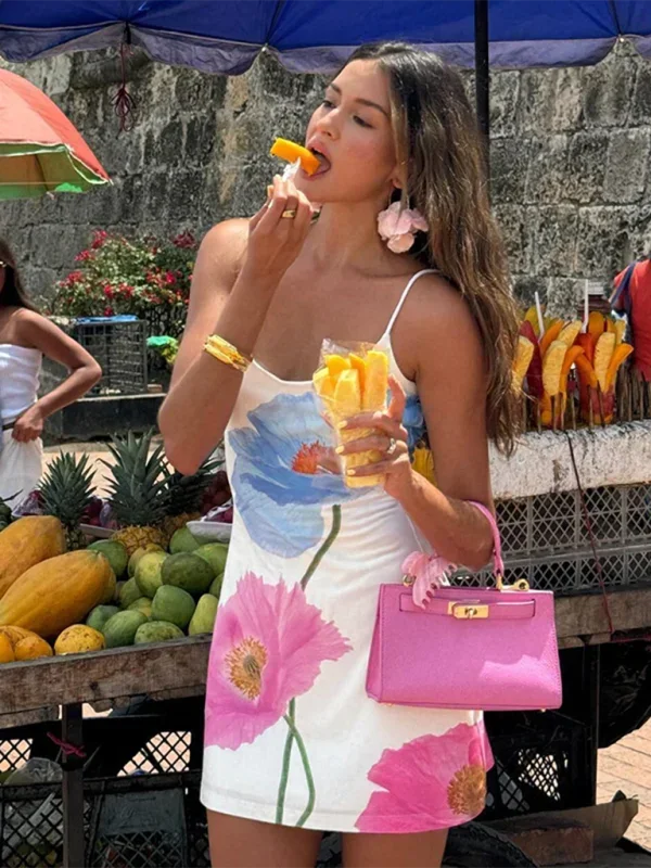 Robe courte blanche en coton avec motifs floraux colorés et bretelles fines, idéale pour les journées d'été à la plage.