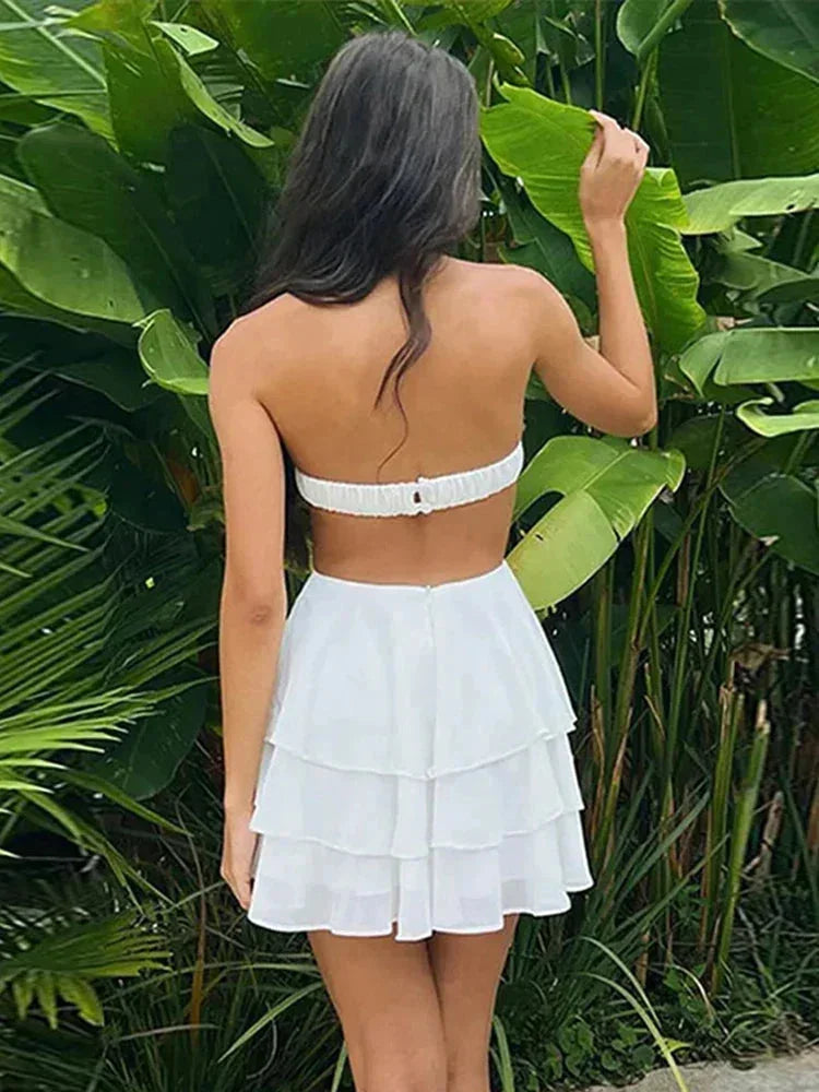 Robe courte blanche à étages, bustier floral sans manches, en tissu léger idéal pour les journées d'été à la plage.