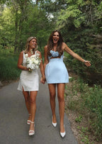 Robe courte bustier en tissu léger, avec motif floral en relief, idéale pour soirées et cocktails.