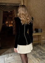 Robe courte noire avec haut structuré et jupe plissée, idéale pour les soirées, en tissu léger et élégant.