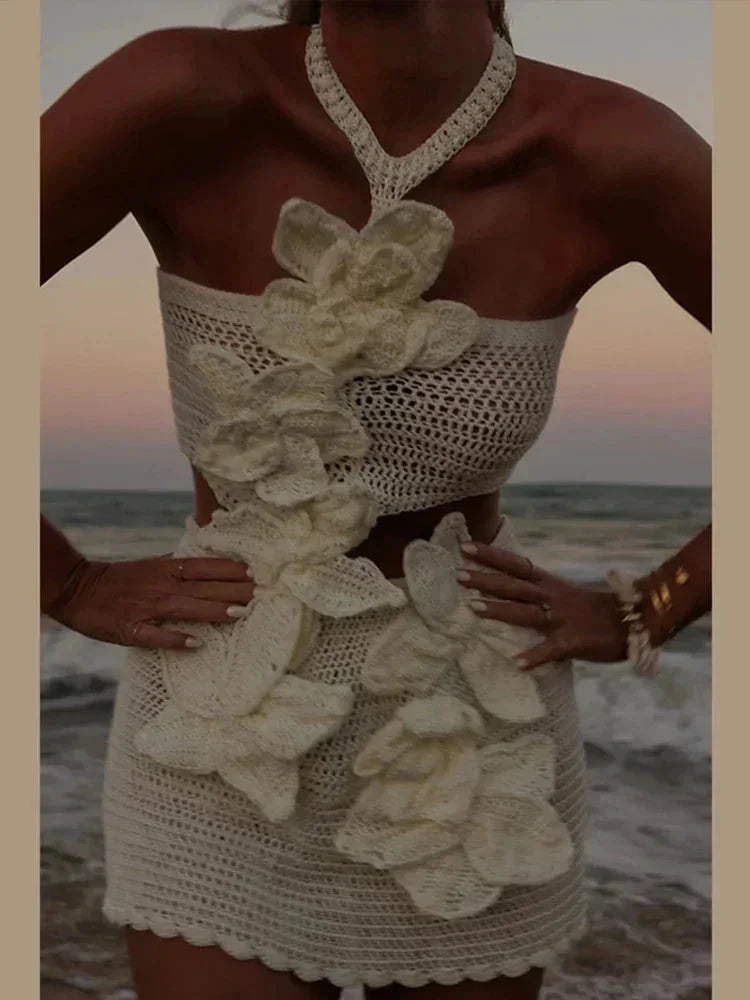 Robe courte en crochet blanche avec fleurs découpées, idéale pour les soirées d'été. Détails floraux et design original.