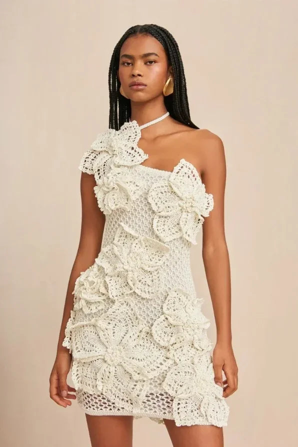 Robe courte en crochet blanc à épaules dénudées, avec volants et motifs floraux, idéale pour les soirées d'été.