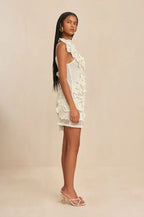 Robe courte en crochet blanc avec épaules dénudées, volants délicats et motif floral, idéale pour les soirées d'été.