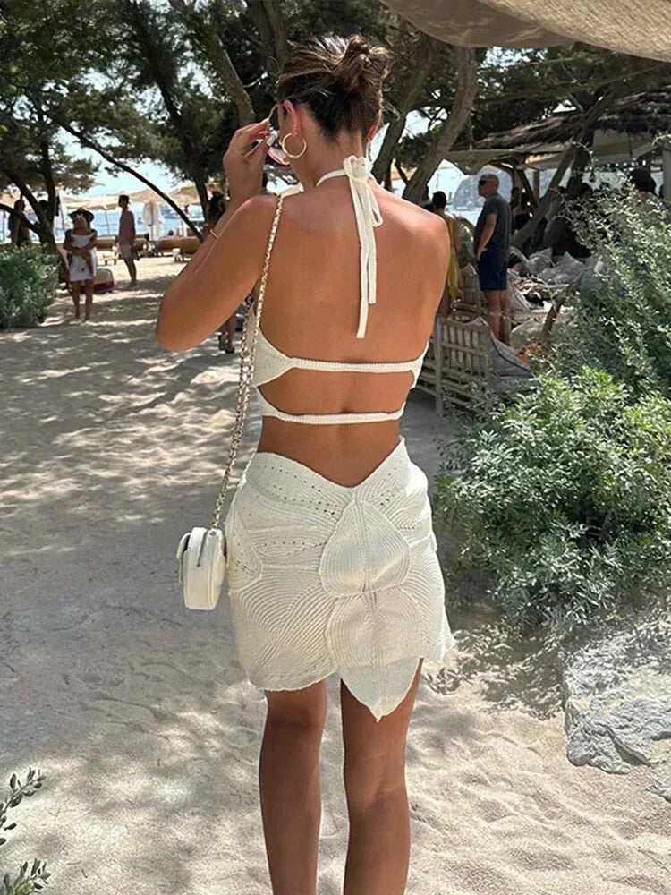 Robe courte en crochet, décolleté licou et découpes, idéale pour l'été à la plage, confectionnée dans un tissu léger et aéré.