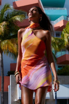 Robe courte à dégradé orange et rose, col licou, tissu fluide, coupe asymétrique pour soirées d'été.