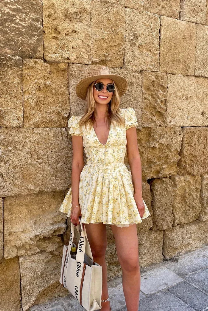 Robe courte jaune à motifs floraux, manches courtes, dos noué et coupe évasée, idéale pour les journées d'été au jardin.