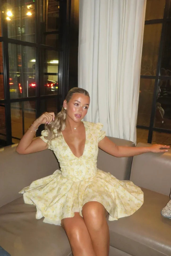 Robe courte jaune fleurie à manches courtes, dos noué et coupe évasée, idéale pour les journées d'été en jardin.