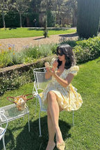 Robe jaune à manches courtes, imprimé fleuri, coupe évasée et dos noué, idéale pour les journées estivales au jardin.