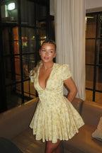 Robe courte jaune à manches courtes, en tissu léger, avec imprimé floral et dos noué, parfaite pour les journées d'été au…