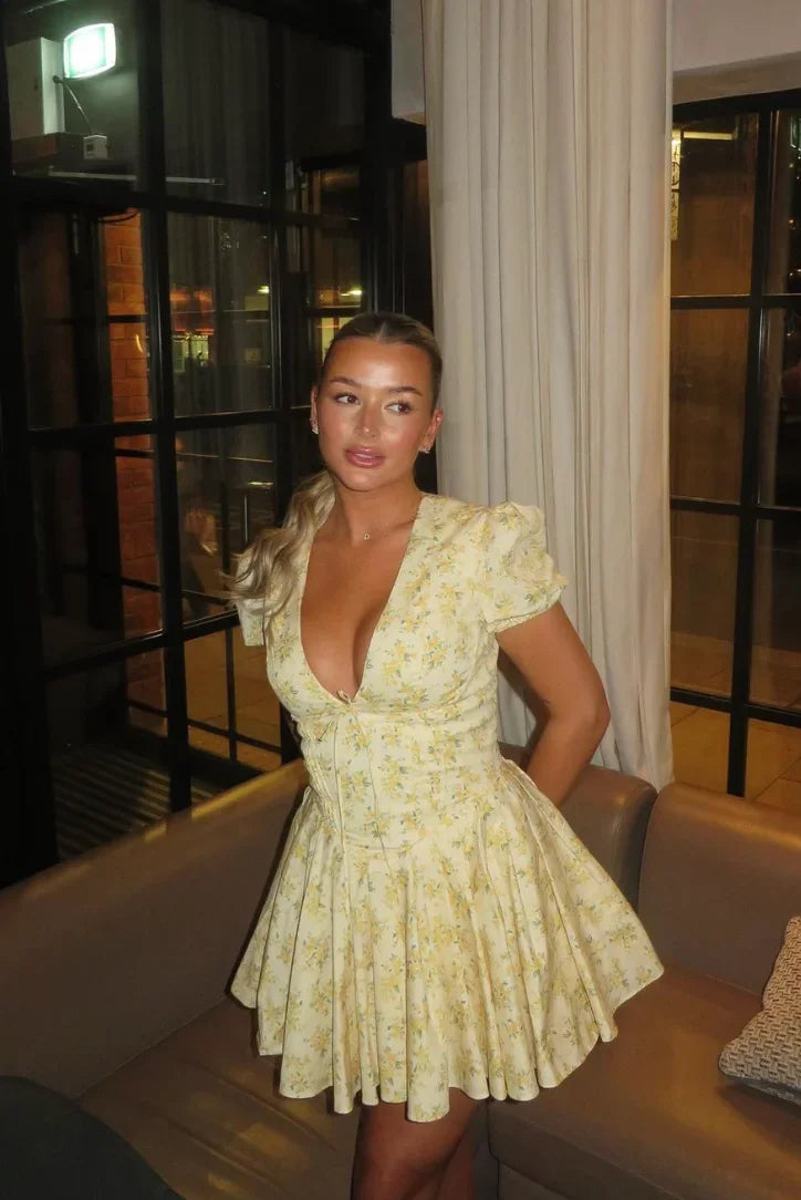 Robe courte jaune à manches courtes, en tissu léger, avec imprimé floral et dos noué, parfaite pour les journées d'été au…