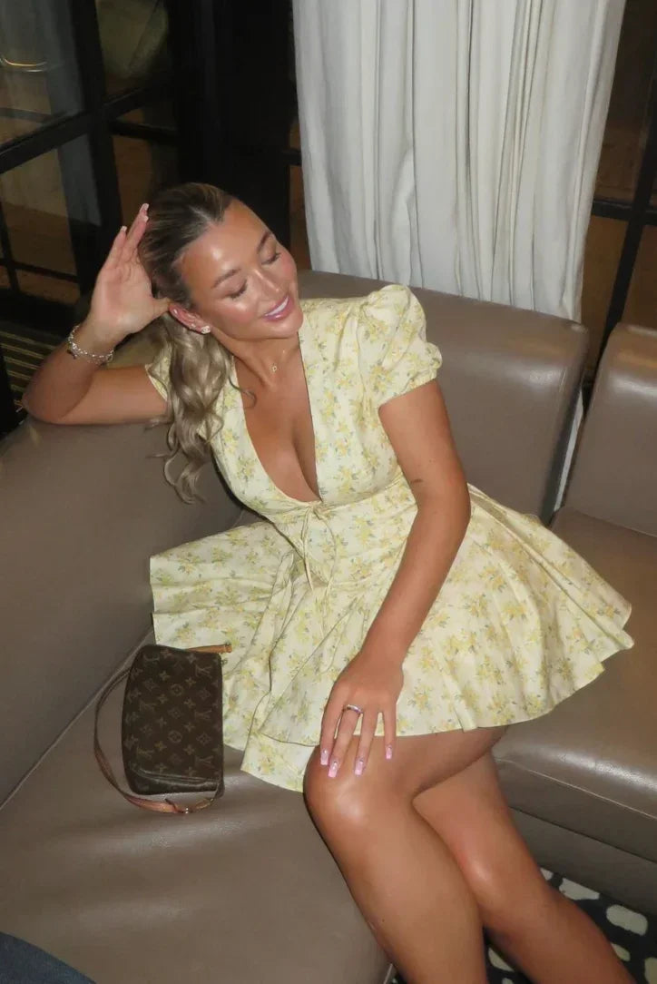 Robe courte jaune à fleurs, manches courtes, dos noué, tissu léger et coupe évasée, idéale pour les jardins d'été.