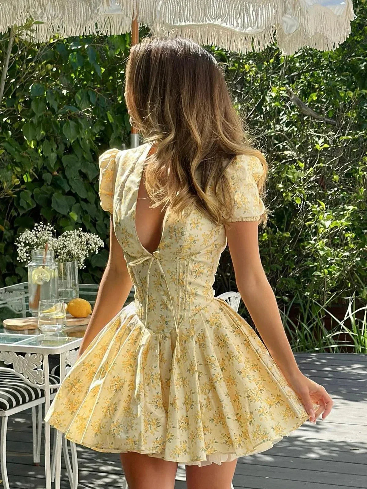 Robe courte jaune à fleurs, manches courtes, dos noué, coupe évasée, parfaite pour les journées d'été au jardin.