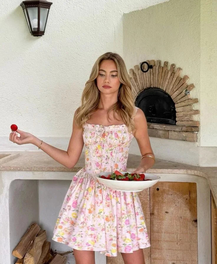 Robe courte fleurie rose à corset, fabriquée en coton léger, avec bretelles larges et motifs floraux pour un style estival.