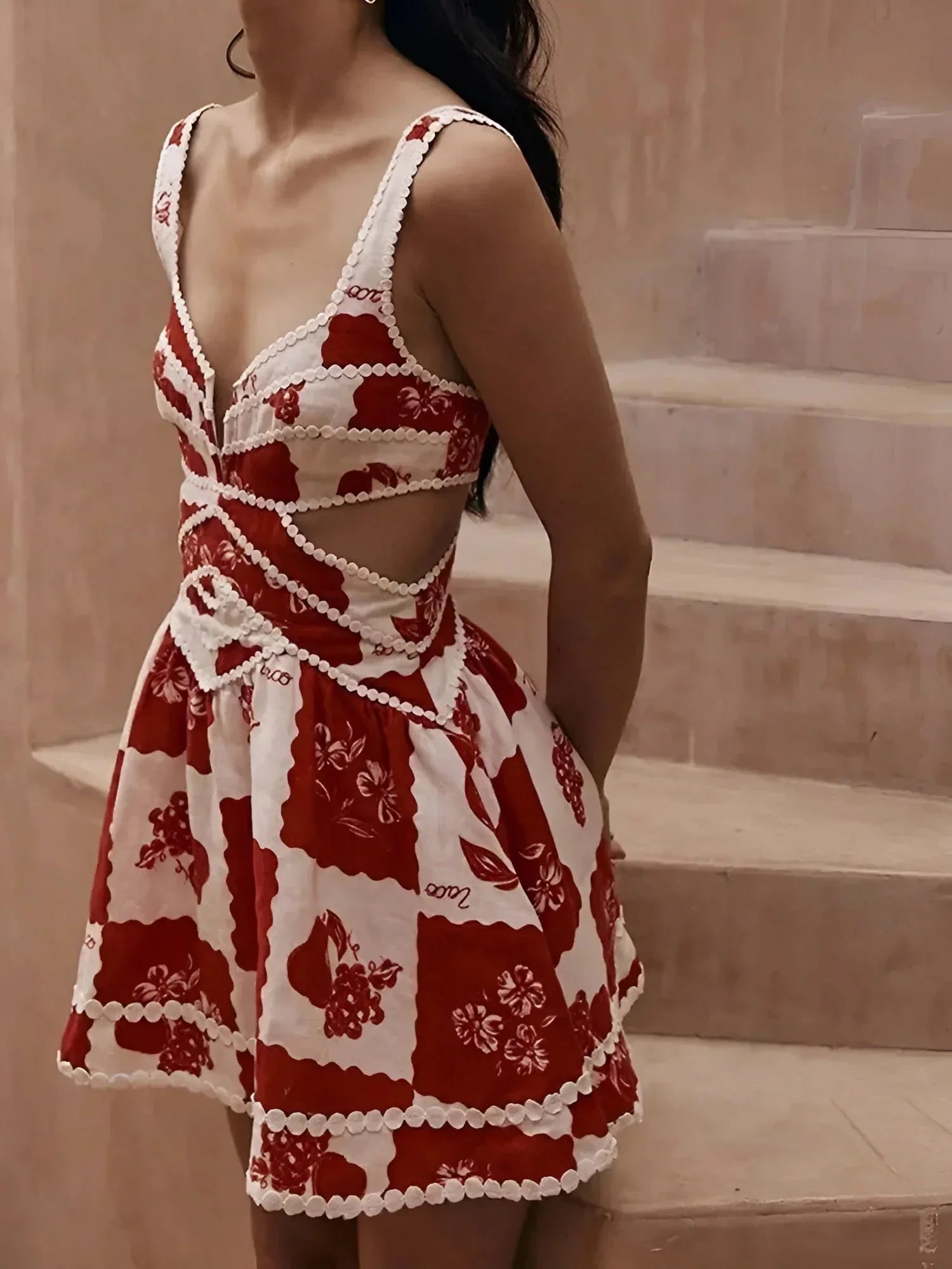 Robe courte florale rouge en coton, avec pompons blancs, idéale pour les journées d'été à la plage.