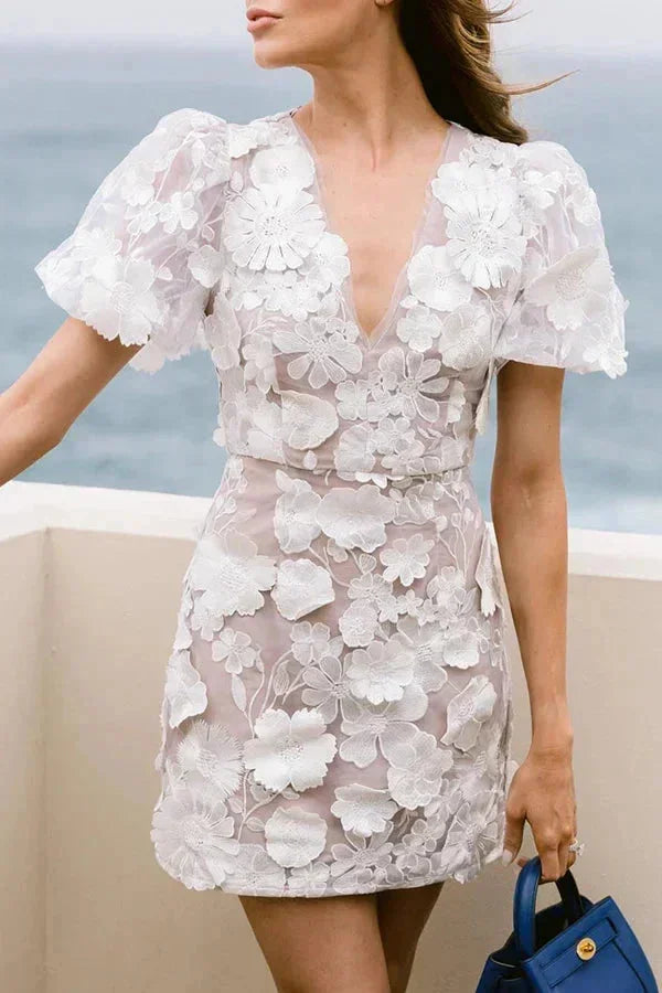 Robe courte florale transparente en dentelle, manches bouffantes, disponible en coloré ou blanc pour des occasions spéciales.