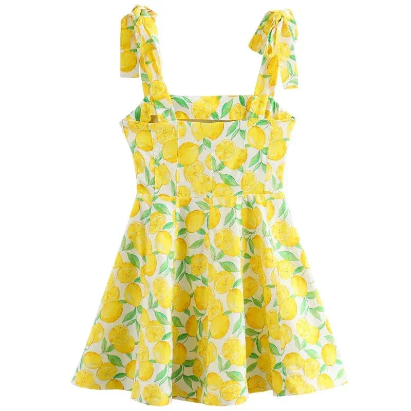 Robe courte sans manches jaune imprimée citron, encolure carrée avec lien, idéale pour une journée d'été à la plage.