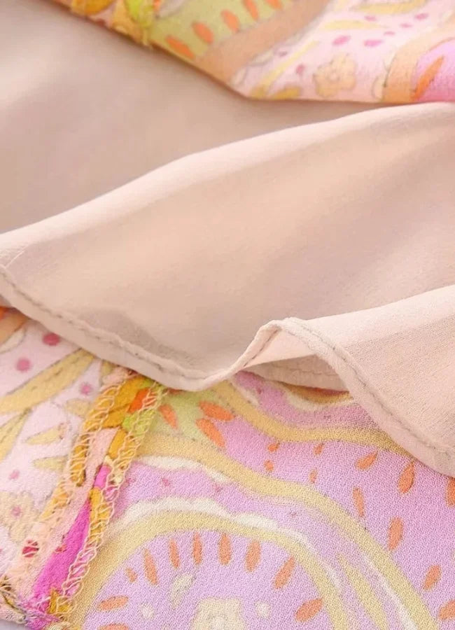 Robe courte estivale col V, manches longues, imprimée rose et jaune, coupe portefeuille en tissu fluide pour la plage.