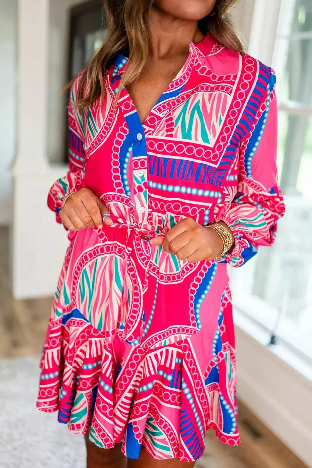 Robe courte à imprimé tribal rose, manches longues, col boutonné, coupe ample en tissu léger idéal pour l'été à la plage.