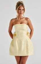 Robe courte jacquard sans bretelles avec grand nœud au dos, en tissu doux et texturé, idéale pour les occasions estivales.