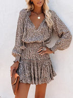 Robe courte léopard en tissu fluide, avec volants, col V et manches longues, idéale pour des soirées élégantes.