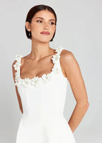 Robe courte noire sans manches, brodée de fleurs blanches, en tissu léger, idéale pour une soirée élégante.