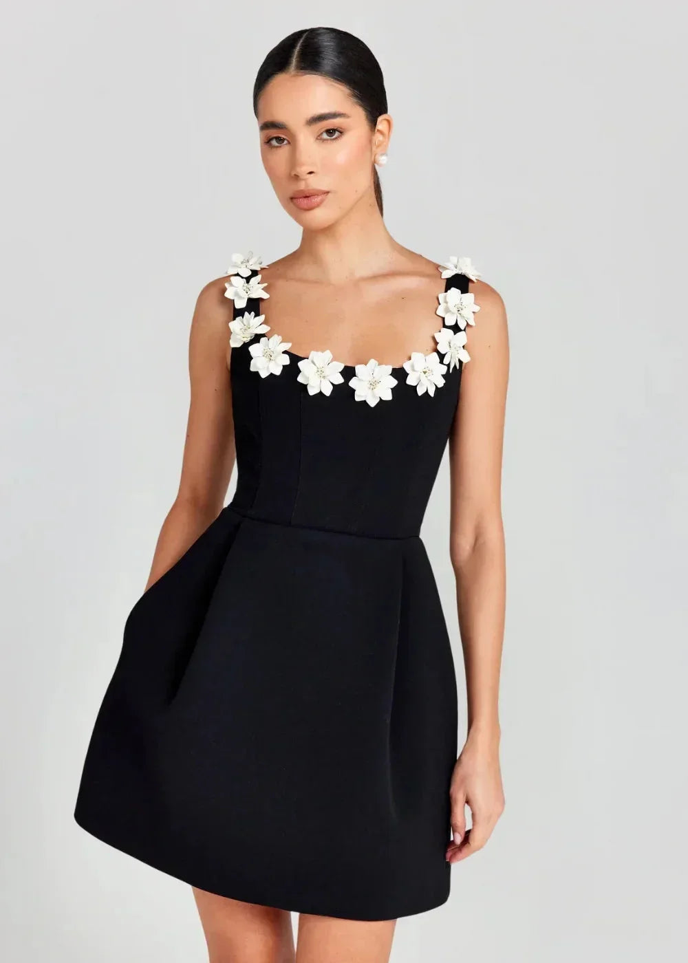 Robe courte noire sans manches, brodée de fleurs blanches, en tissu léger, parfaite pour une soirée élégante.