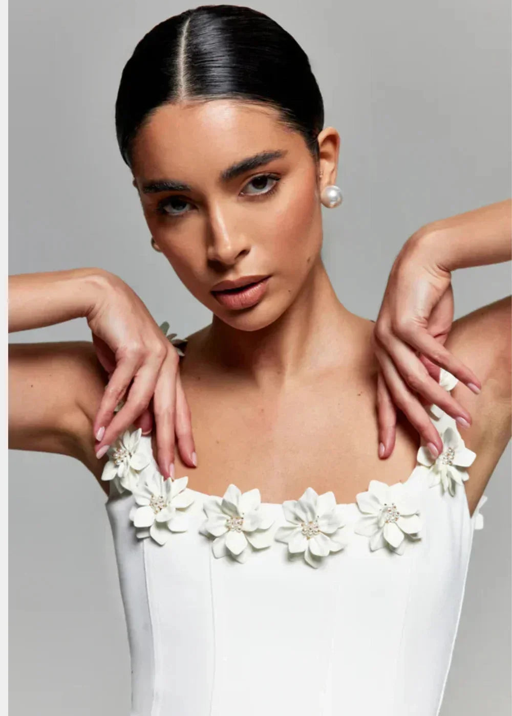 Robe courte noire sans manches, en tissu léger, ornée de broderies florales blanches pour une soirée élégante.