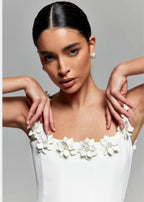 Robe courte noire sans manches, en tissu léger, ornée de broderies florales blanches pour une soirée élégante.