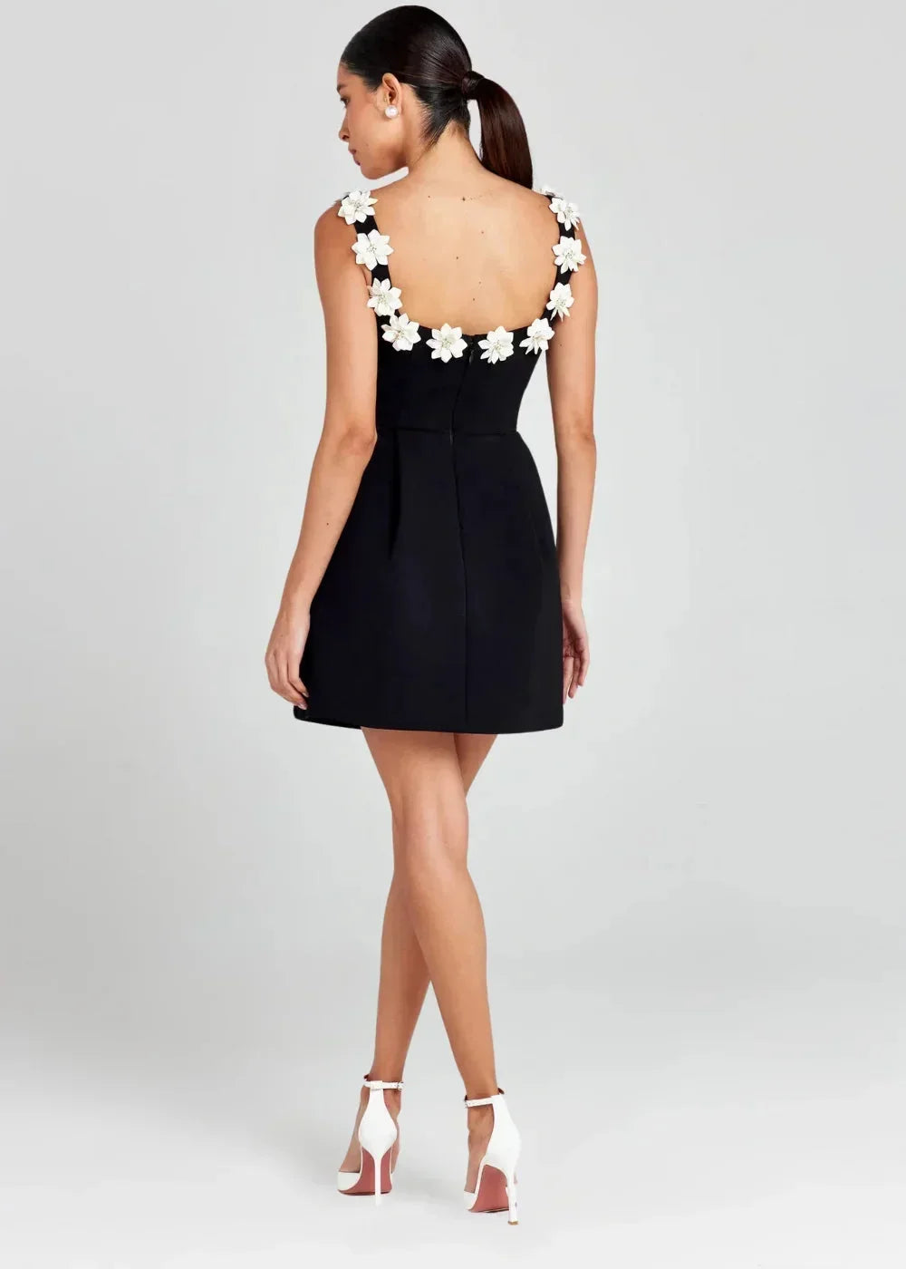 Robe courte noire sans manches, brodée de fleurs blanches, en tissu léger, idéale pour des soirées élégantes.