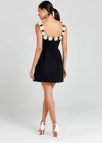 Robe courte noire sans manches, brodée de fleurs blanches, en tissu léger, idéale pour des soirées élégantes.