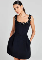 Robe courte noire sans manches avec broderie de fleurs blanches, en tissu léger, idéale pour une soirée élégante.